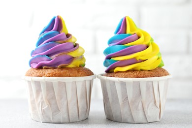 Photo of Tasty cupcakes with colorful cream on white table, closeup