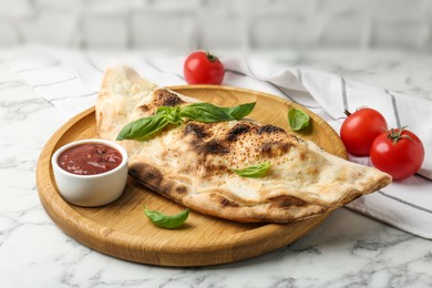 Photo of Delicious calzone served on white marble table