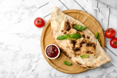 Photo of Delicious calzone served on white marble table, top view. Space for text