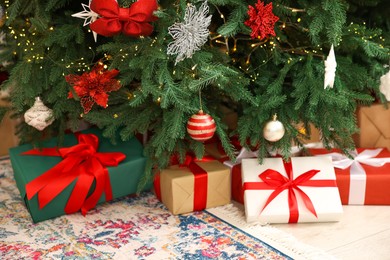 Photo of Many gifts under Christmas tree indoors, closeup