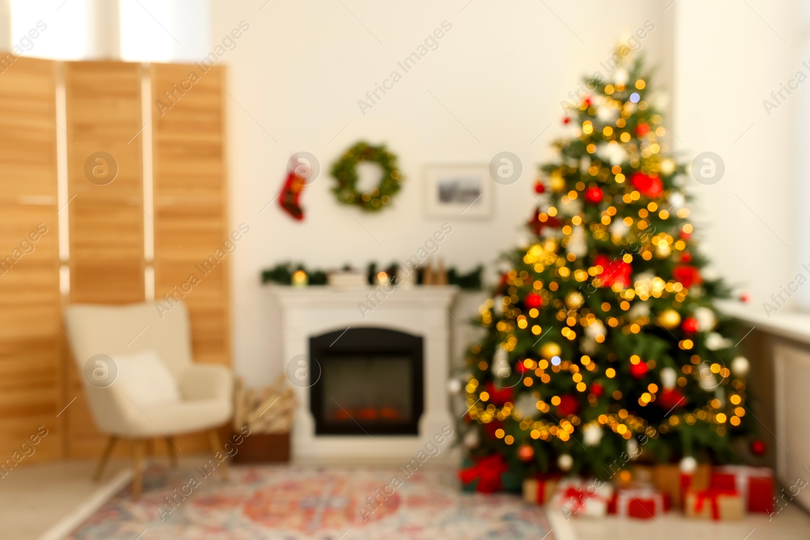 Photo of Blurred view of decorated Christmas tree near fireplace in room. Festive interior design