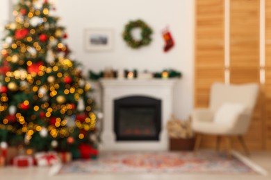 Blurred view of decorated Christmas tree near fireplace in room. Festive interior design