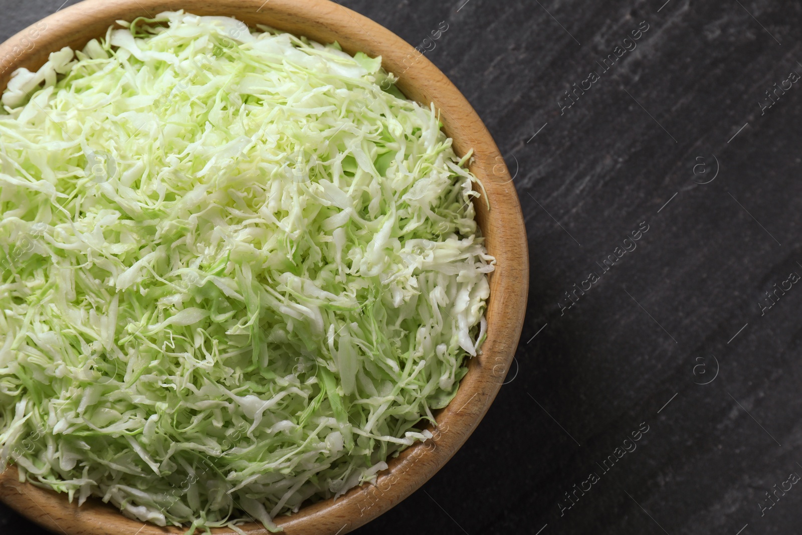 Photo of Fresh shredded cabbage on black table, top view