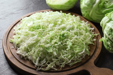 Photo of Fresh shredded cabbage on black table, closeup