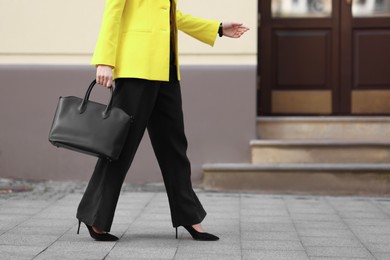 Photo of Businesswoman in stylish suit with bag outdoors, closeup. Space for text