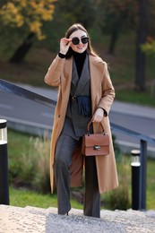 Photo of Smiling businesswoman in stylish suit on stairs outdoors