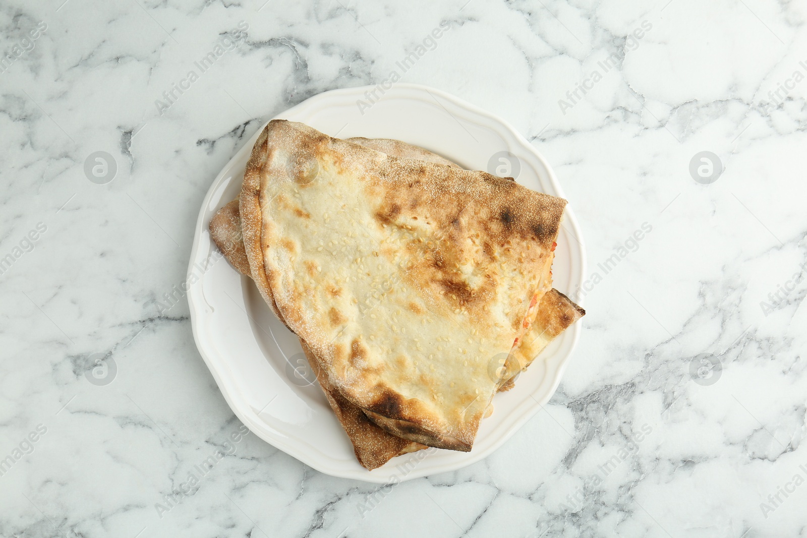 Photo of Halves of tasty calzone on white marble table, top view