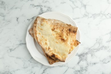 Photo of Halves of tasty calzone on white marble table, top view