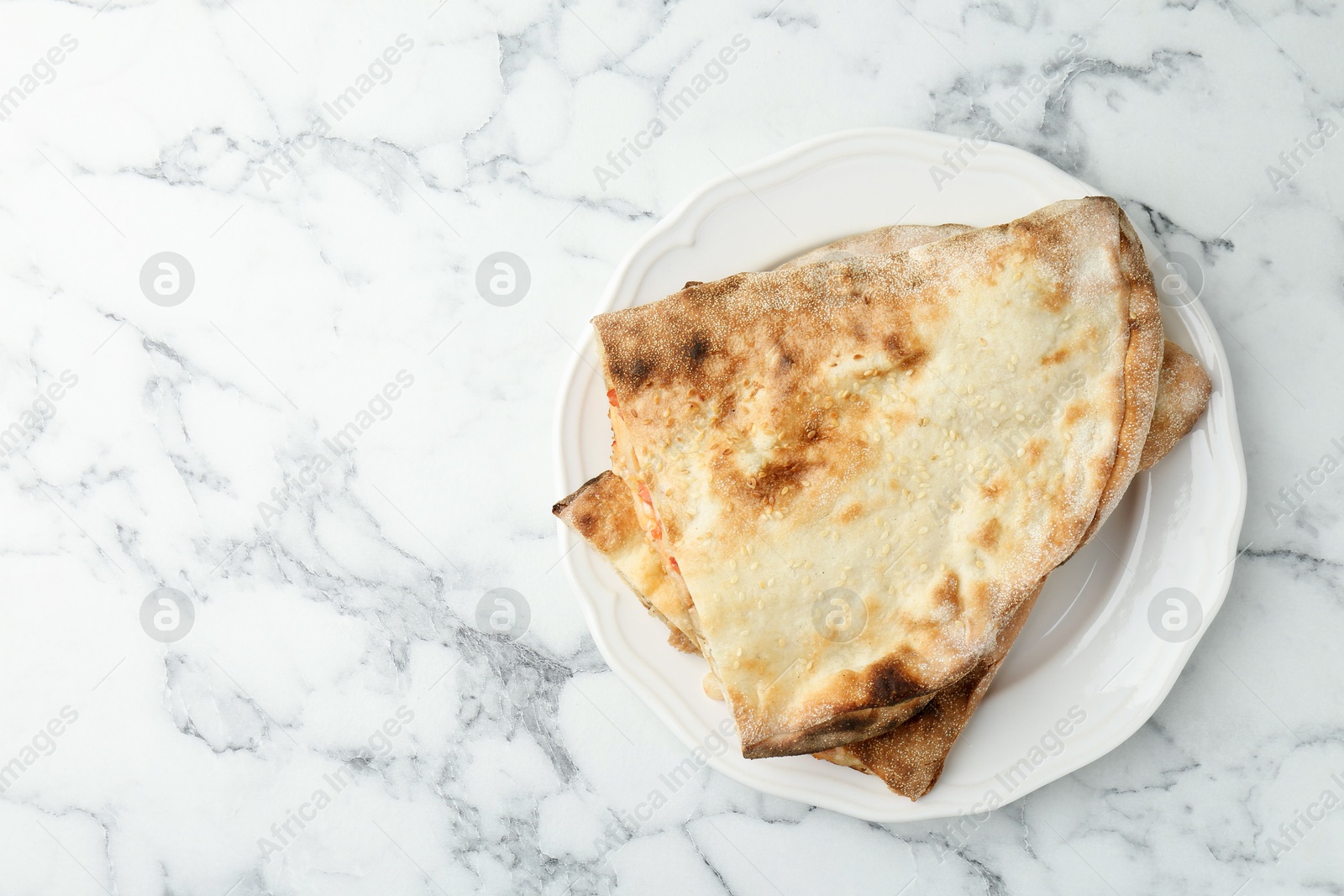 Photo of Halves of tasty calzone on white marble table, top view. Space for text