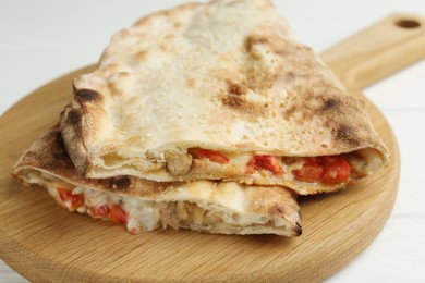 Photo of Halves of tasty calzone with meat, cheese and tomato on white wooden table, closeup