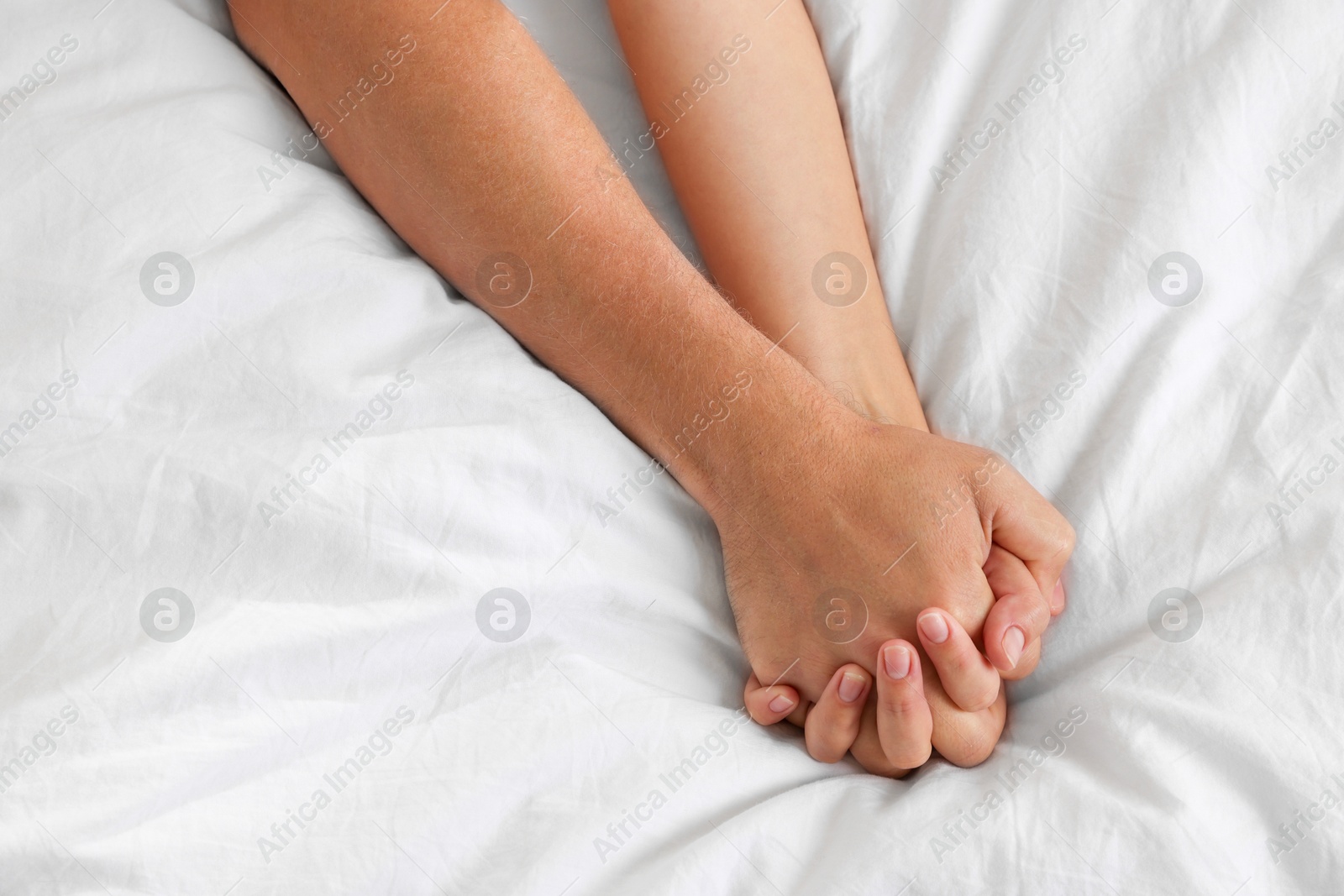 Photo of Lovely couple holding hands in bed, top view