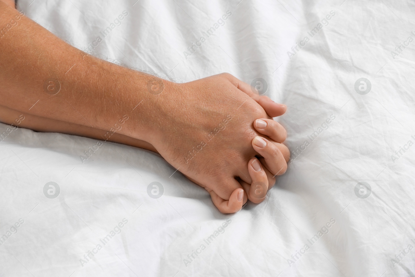 Photo of Lovely couple holding hands in bed, top view