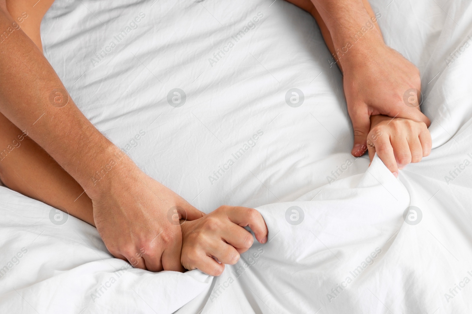 Photo of Lovely couple holding hands in bed, top view