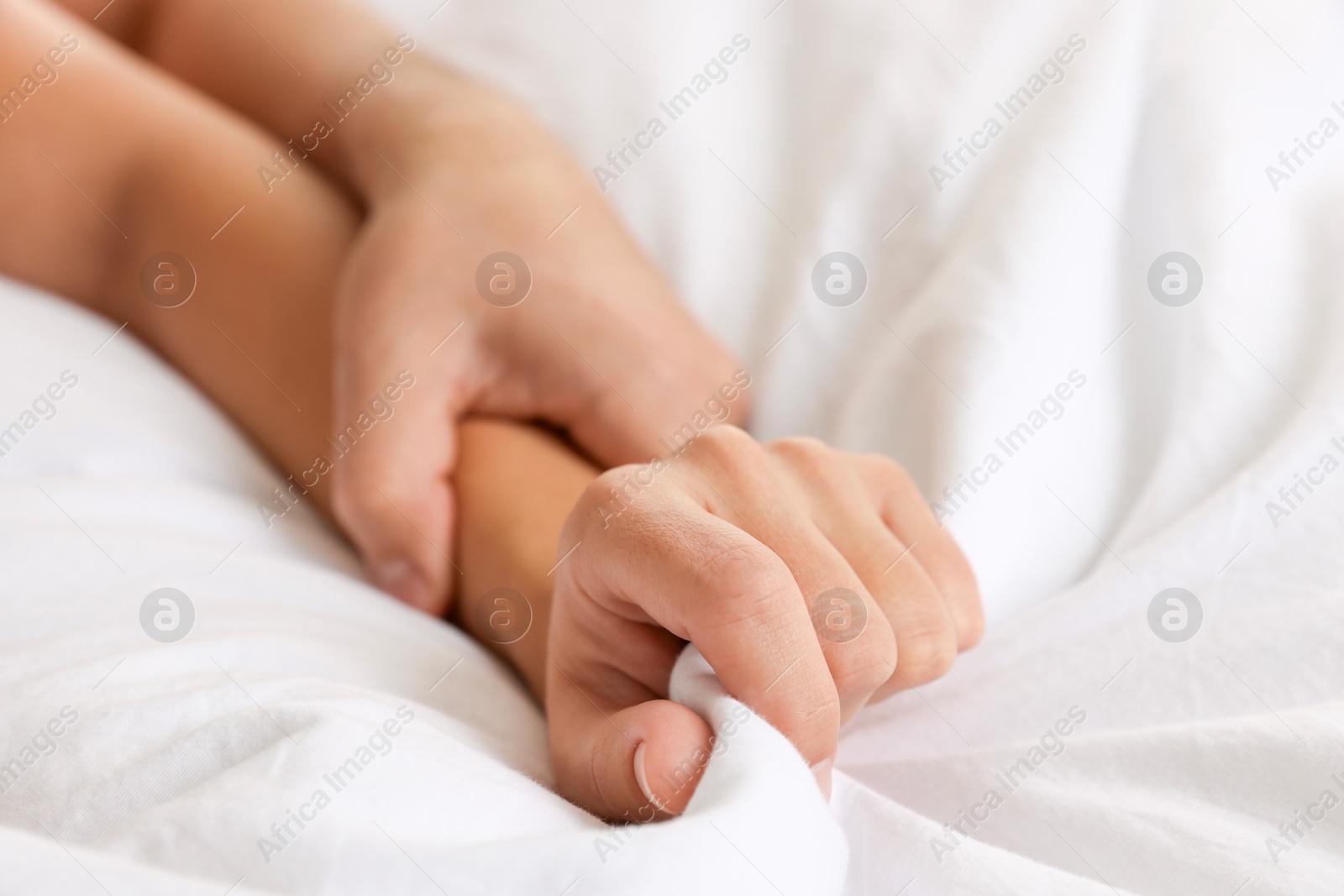 Photo of Lovely couple holding hands in bed, closeup