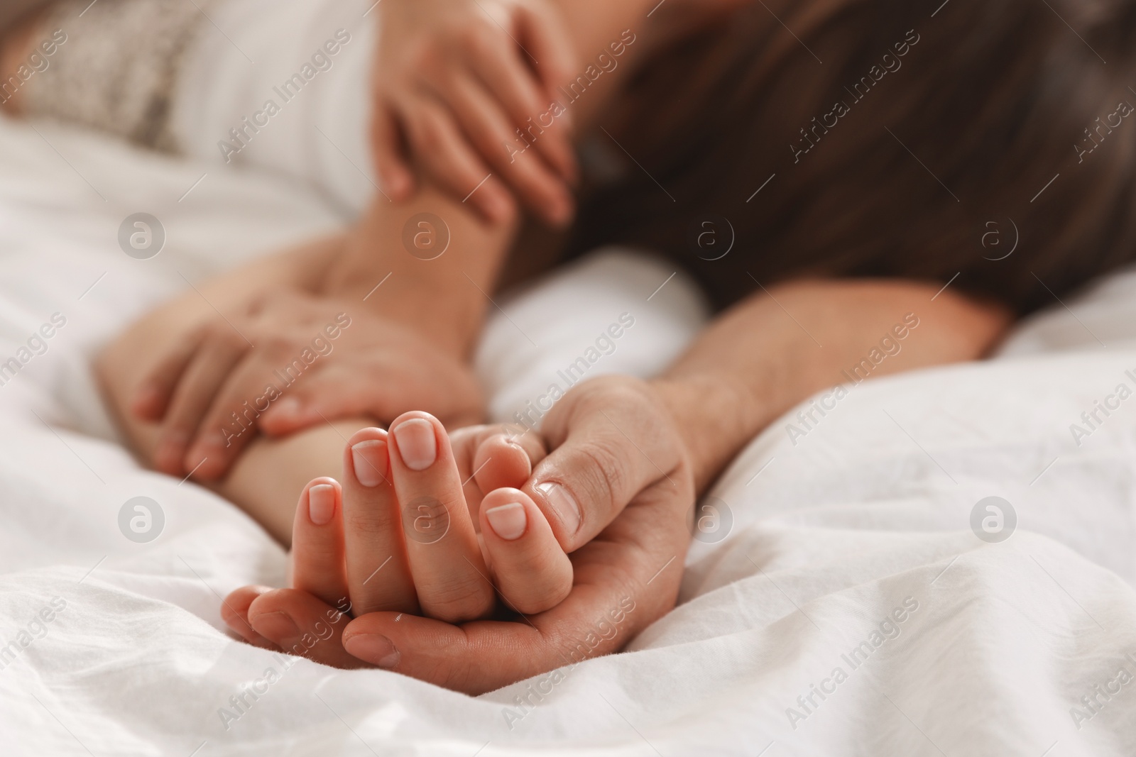 Photo of Lovely couple holding hands in bed, closeup