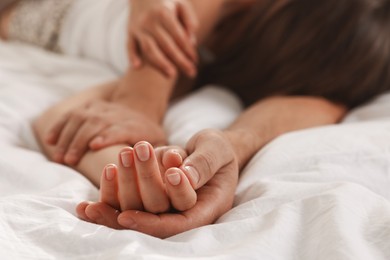 Lovely couple holding hands in bed, closeup