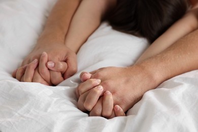 Photo of Lovely couple holding hands in bed, closeup