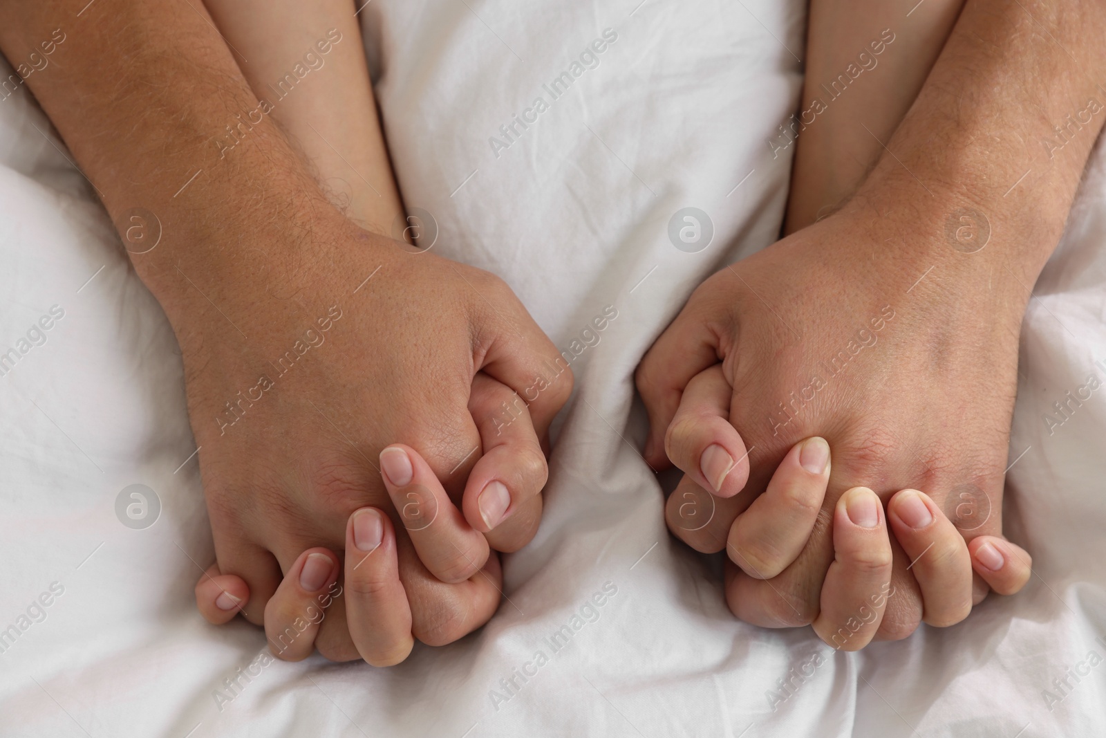 Photo of Lovely couple holding hands in bed, closeup