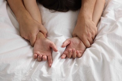 Photo of Lovely couple holding hands in bed, closeup