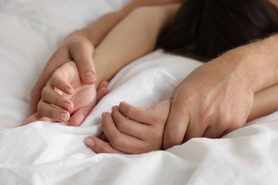 Photo of Lovely couple holding hands in bed, closeup