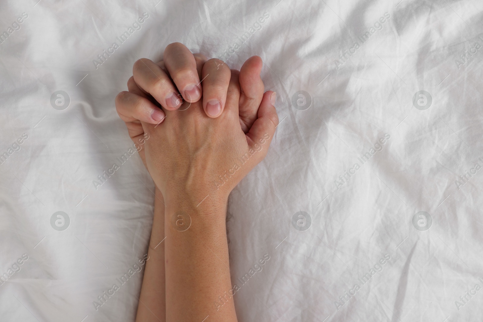 Photo of Lovely couple holding hands in bed, top view