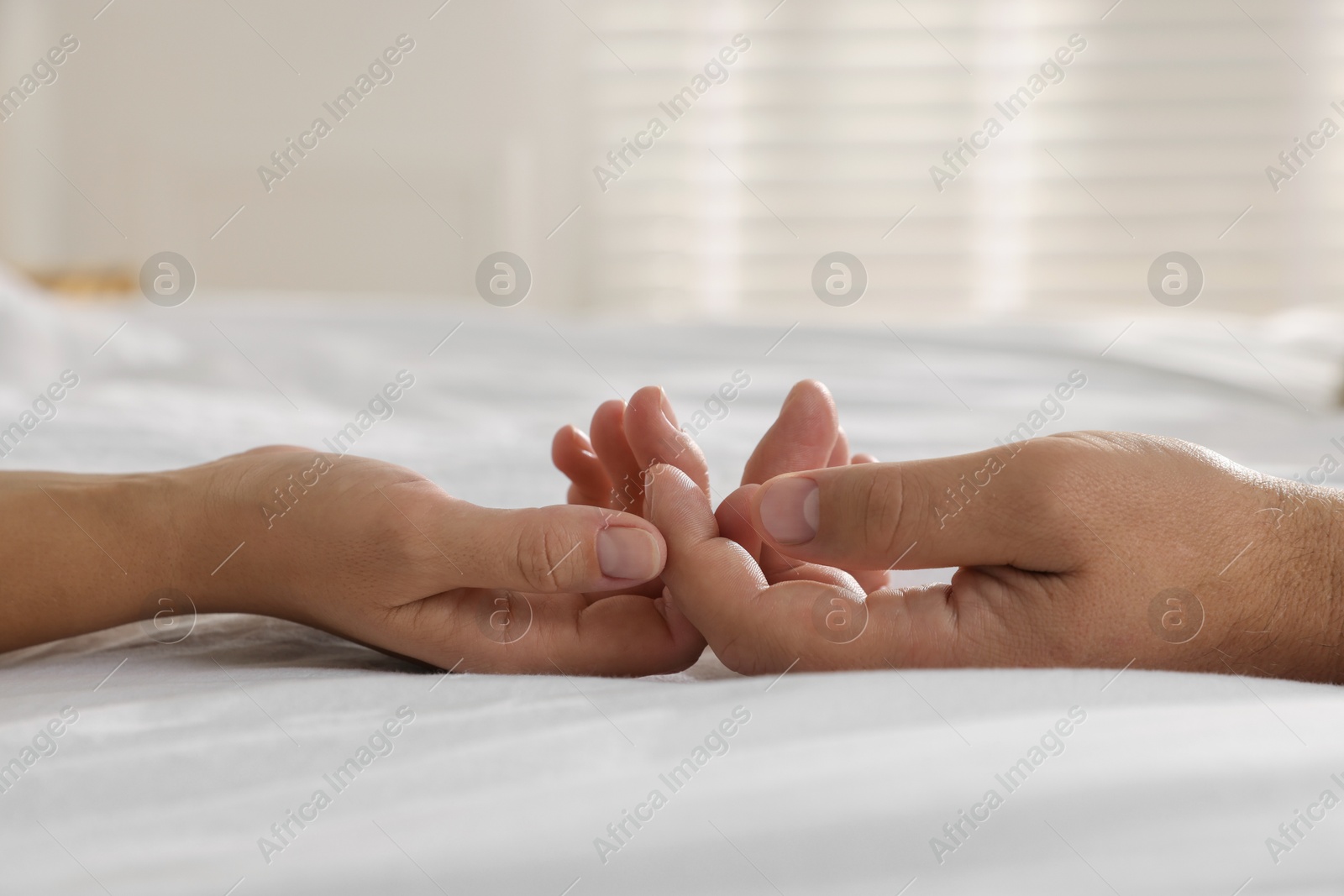 Photo of Lovely couple holding hands in bed, closeup