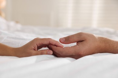 Photo of Lovely couple holding hands in bed, closeup