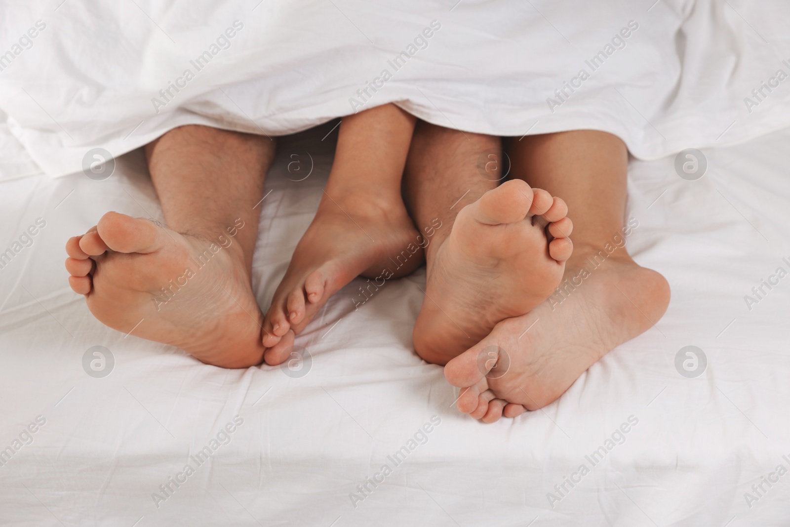 Photo of Couple lying in bed with white sheets, closeup