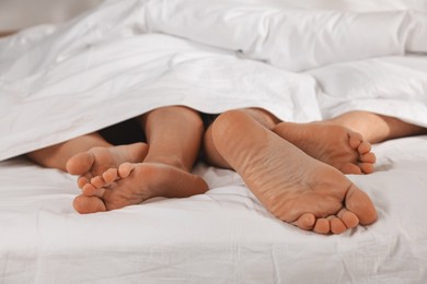 Photo of Couple lying in bed with white sheets, closeup