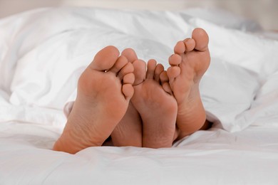 Photo of Couple lying in bed with white sheets, closeup