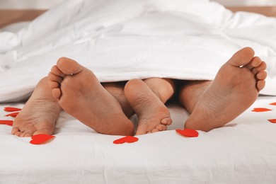 Photo of Couple lying in bed with red paper hearts, closeup