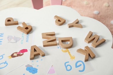 Photo of Learning alphabet. Different wooden letters and pictures on white table indoors