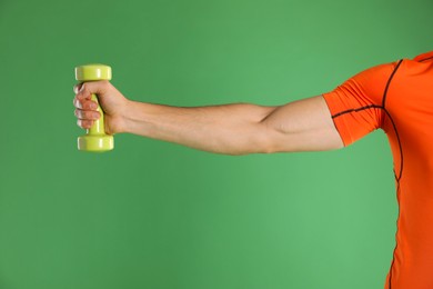 Photo of Man exercising with dumbbell on green background, closeup