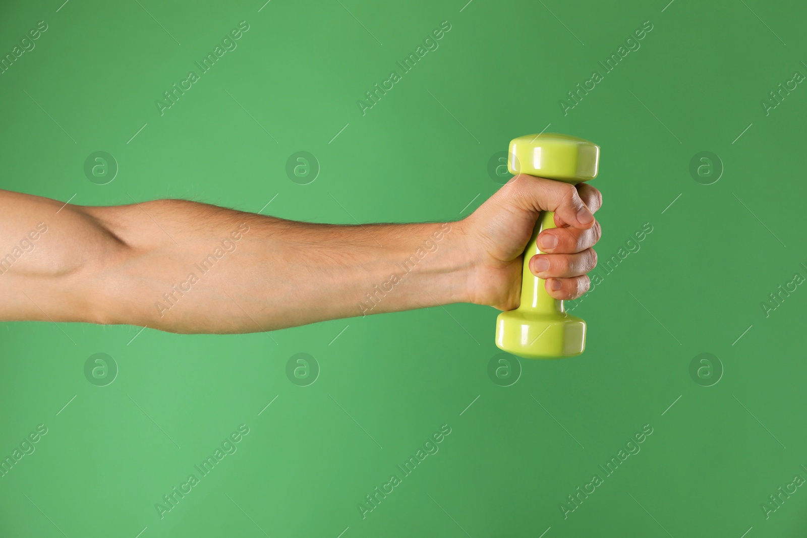 Photo of Man exercising with dumbbell on green background, closeup