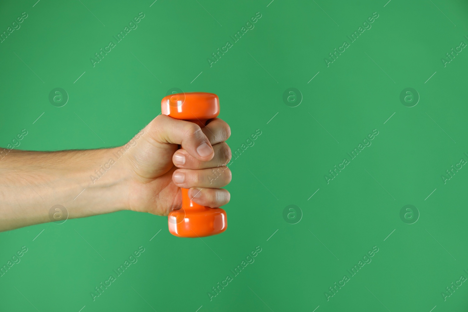 Photo of Man exercising with dumbbell on green background, closeup. Space for text