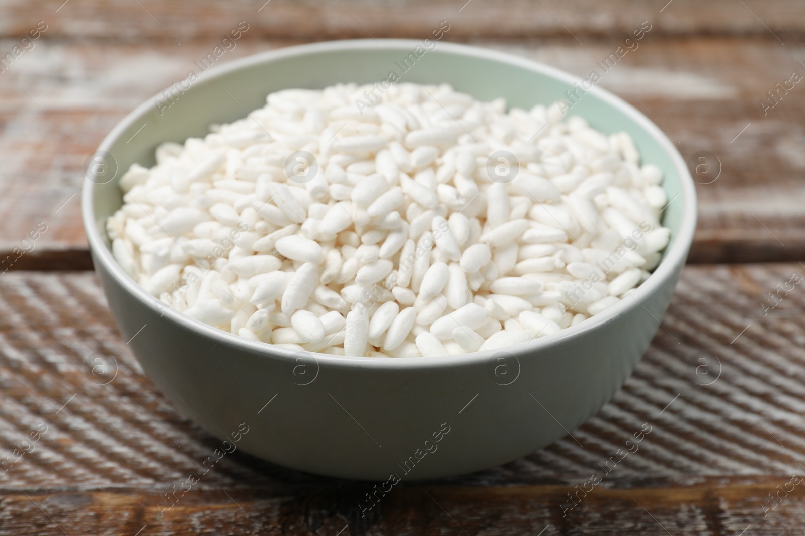 Photo of Puffed rice in bowl on wooden table, closeup