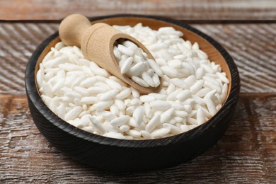 Photo of Puffed rice in bowl and scoop on wooden table, closeup