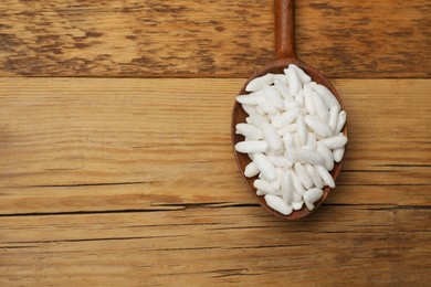 Photo of Puffed rice in spoon on wooden table, top view. Space for text