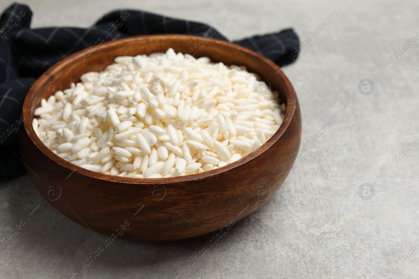 Photo of Puffed rice in bowl on light grey table, closeup