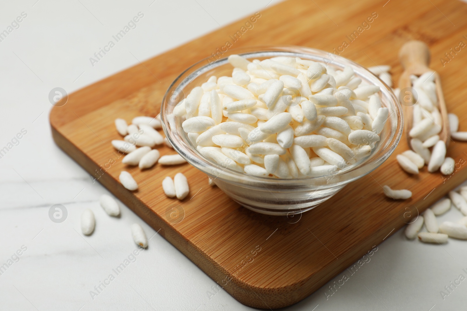 Photo of Puffed rice in bowl on white marble table, closeup