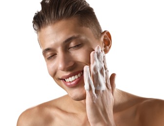 Smiling man washing his face with cleansing foam on white background