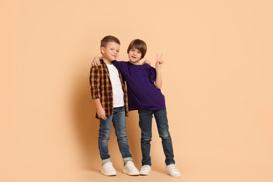 Photo of Full length portrait of cute brothers on beige background