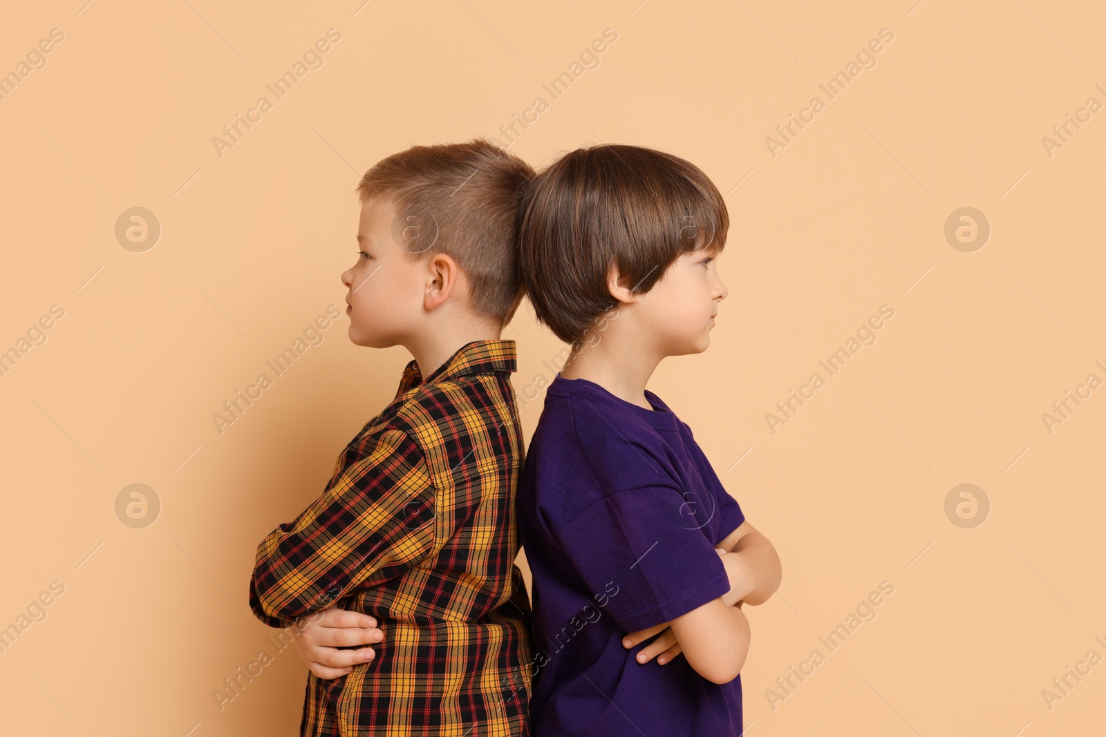 Photo of Upset brothers turned away from each other on beige background