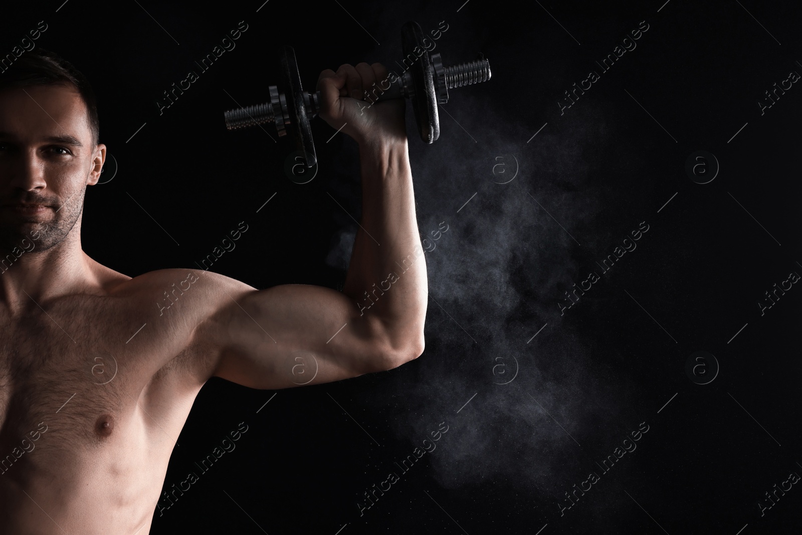 Photo of Man with talcum powder on hand training with barbell against black background. Space for text