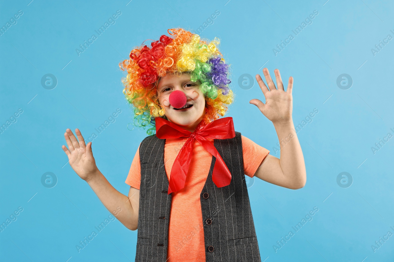 Photo of Happy boy dressed like clown on light blue background. Surprise party