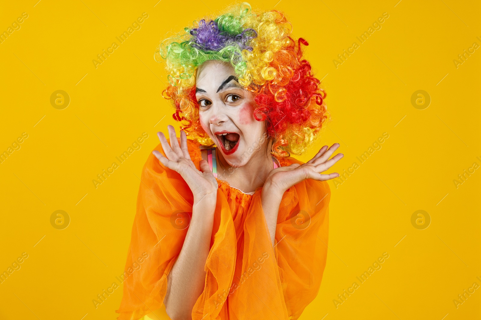 Photo of Cute girl dressed like clown on yellow background. Surprise party