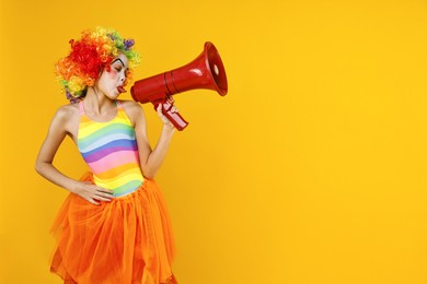 Photo of Cute girl dressed like clown with megaphone on yellow background, space for text. Surprise party