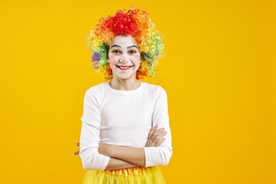 Photo of Happy girl dressed like clown on yellow background. Surprise party