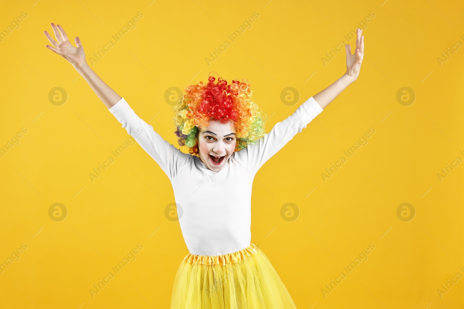 Photo of Happy girl dressed like clown on yellow background. Surprise party