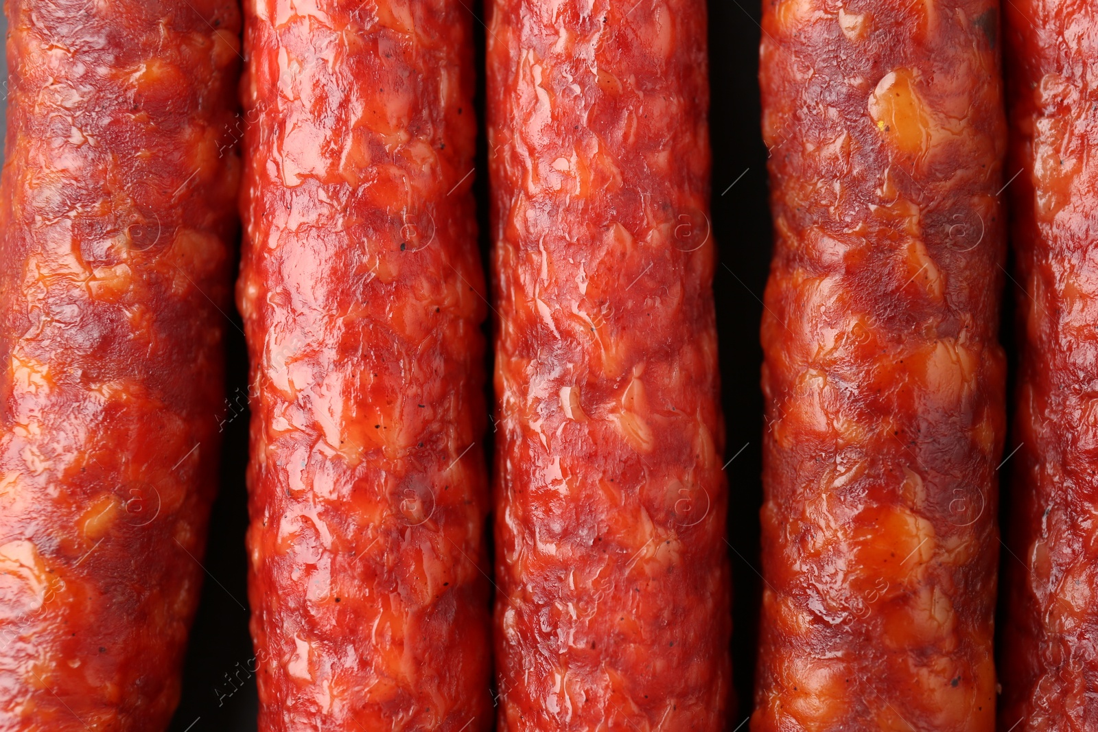 Photo of Many tasty smoked sausages as background, top view